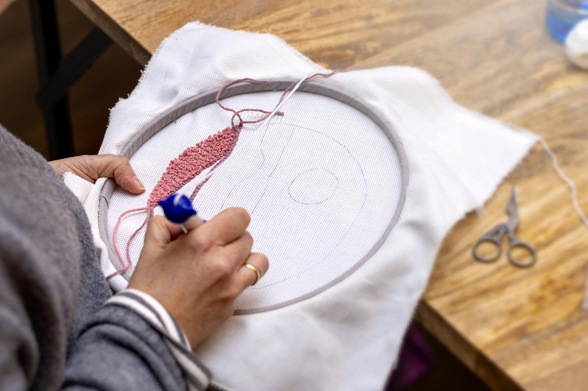 Hands finishing embroidery on hoop in studio